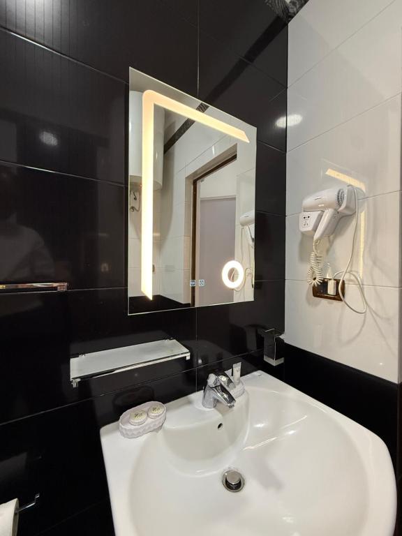 Black tile bathroom with rectangular lit mirror